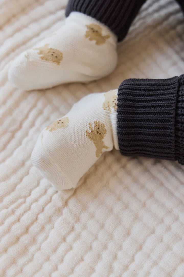 Baby socks with bear designs on a textured surface