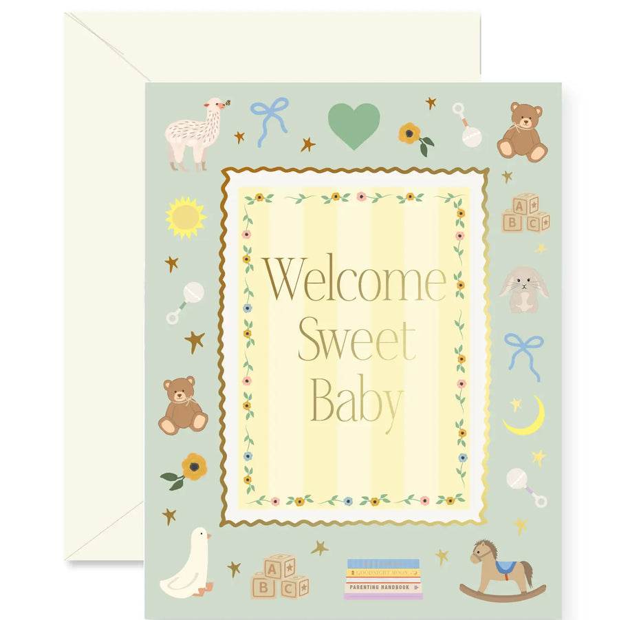 A baby shower greeting card with a pale green background and a cream envelope behind it. The card features the words 'Welcome Sweet Baby' in a decorative central panel surrounded by illustrations of baby-themed items including a lamb, teddy bear, bunny, rocking horse, stars, and blocks.