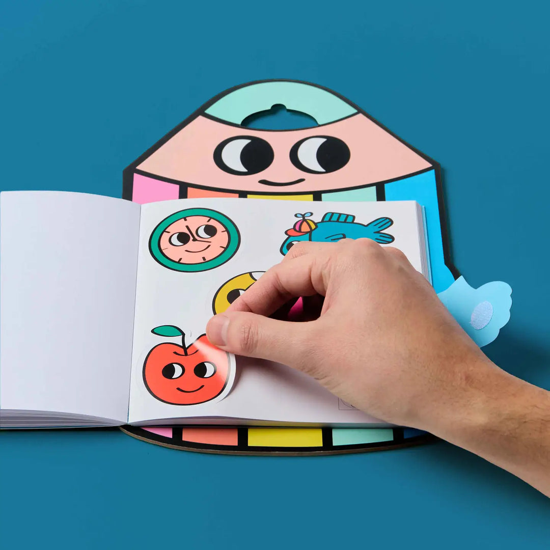 a hand peeling back one of the stickers on the page. 