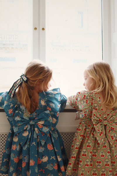 little girls peering out the window showing off the back of their dresses and their dramatic bows. 