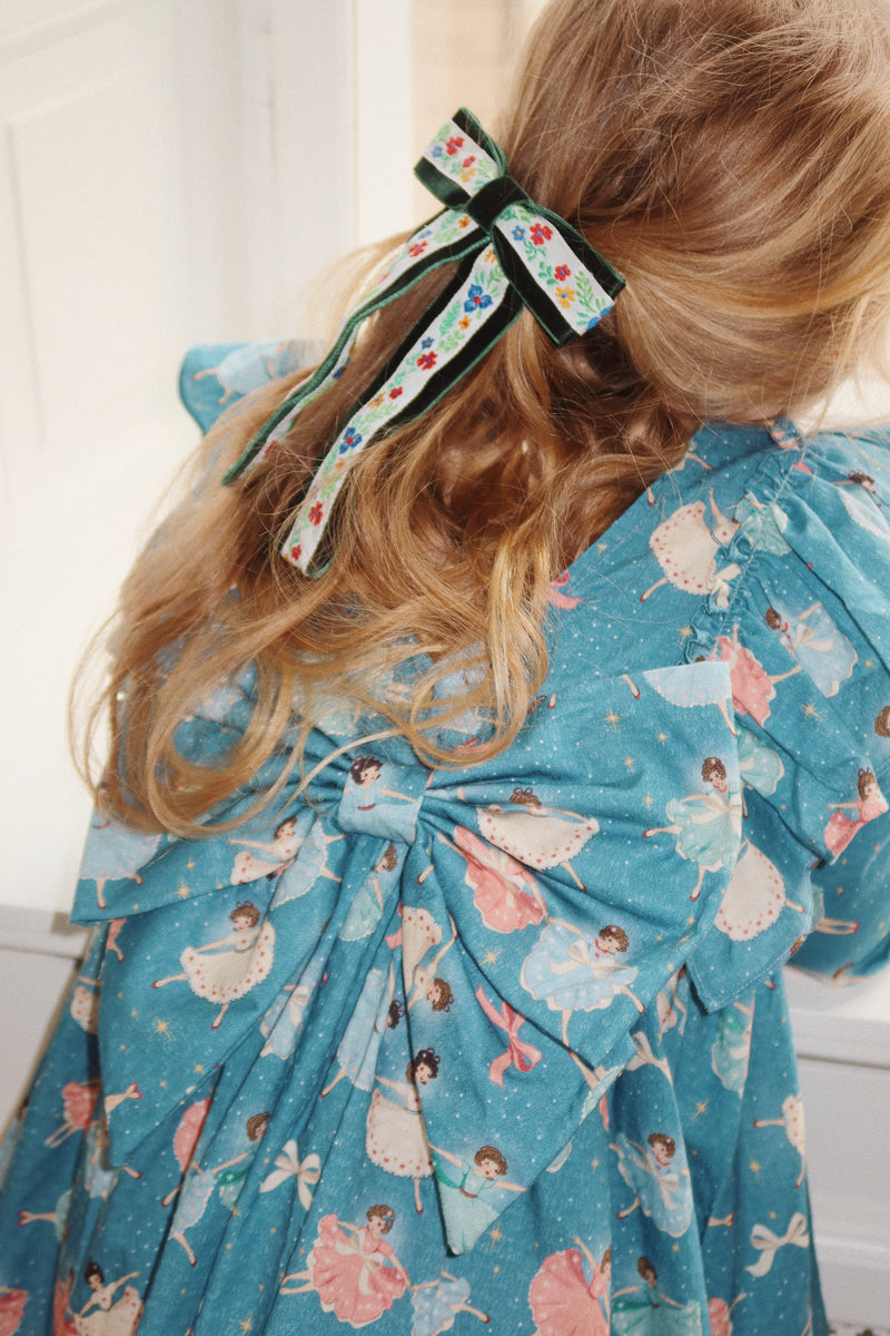 close up of the bow, the dress and the print. the ballerinas are vintage looking in pink, blue and white tutus. 