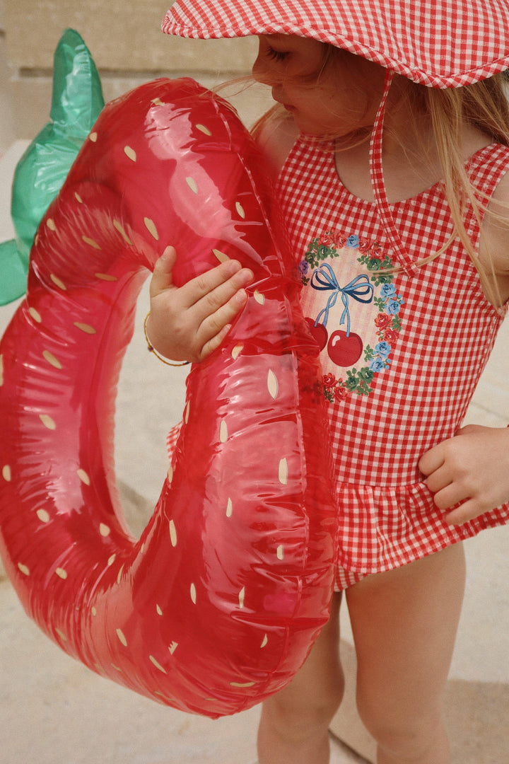 young girl holding the strawberry swim ring. 