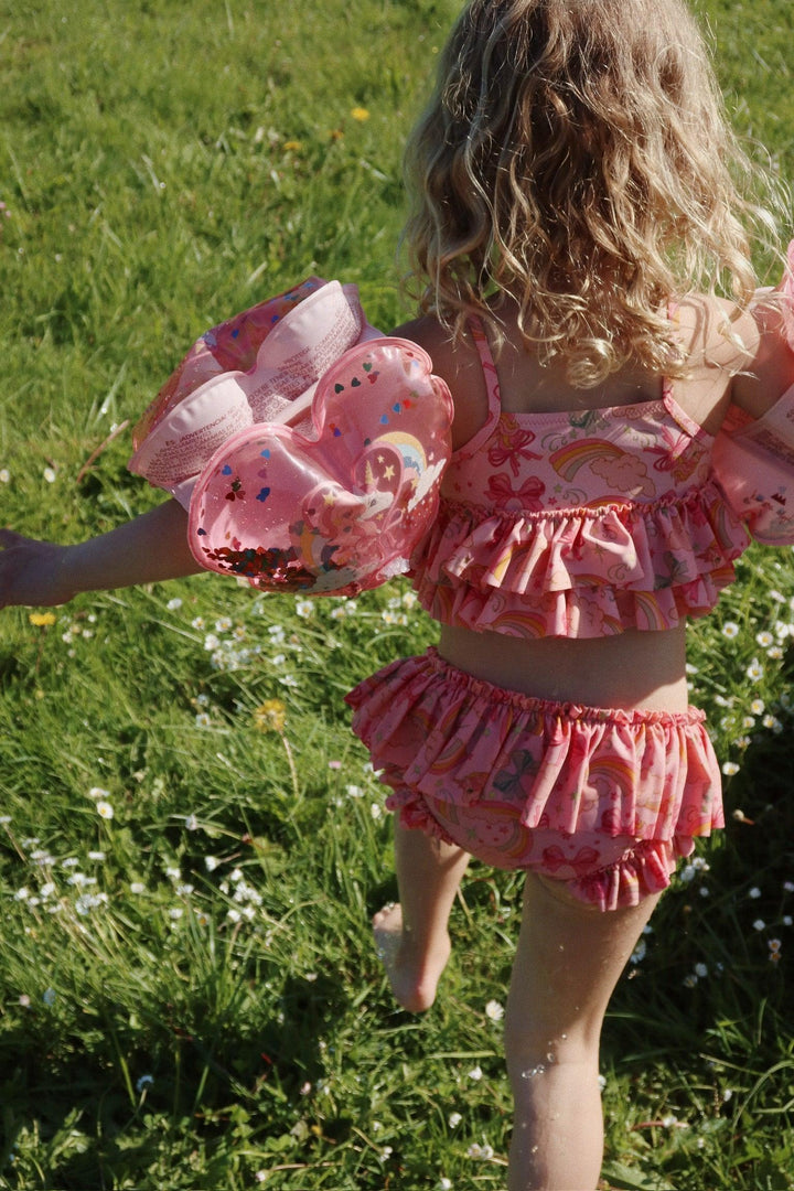 picture of the bathing suit from back. young girl wearing it showing ruffles on the bottom of the top and the top of the bottom. 