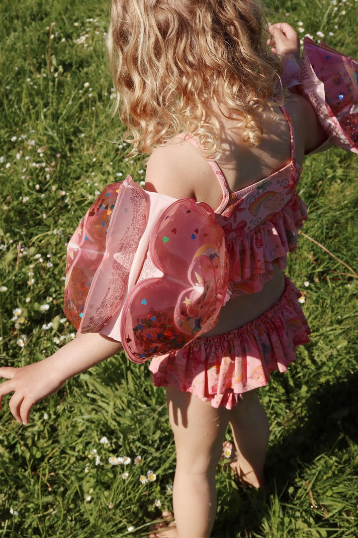 another shot of the bathing suit on a young girl a view of the pink and all the ruffles in the sun from up high.