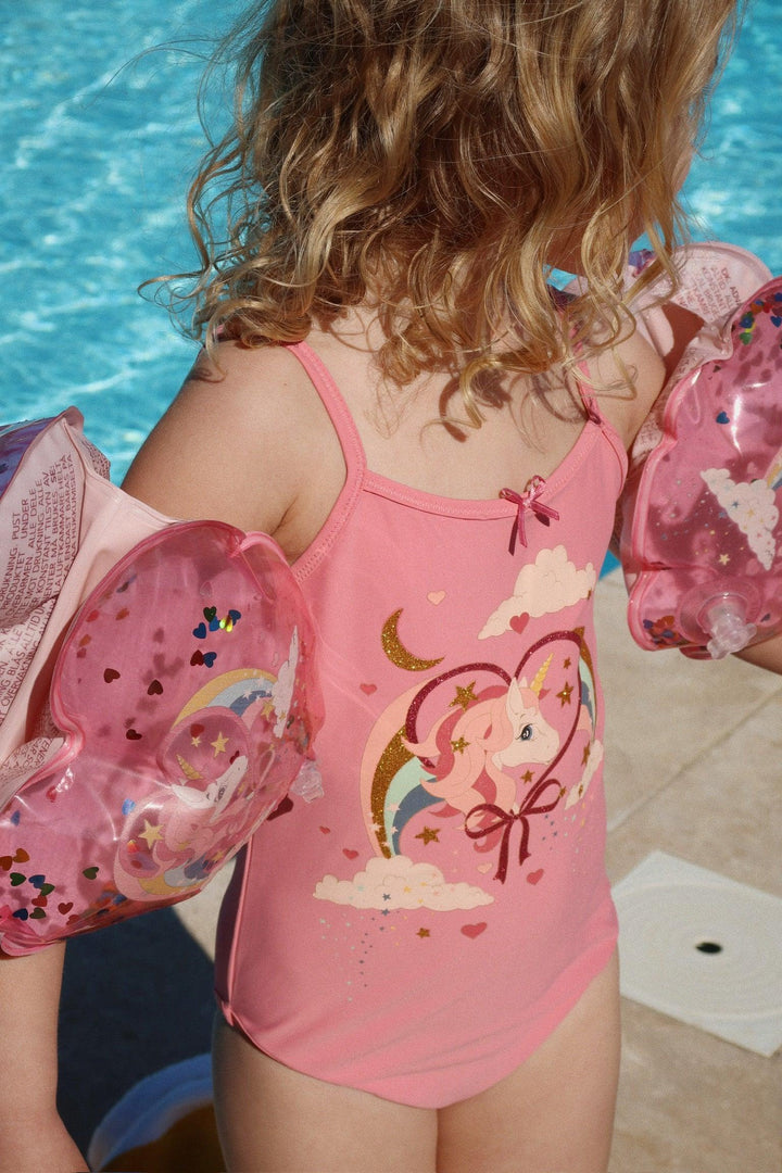 picture of young child wearing the water wings with a unicorn on the front and glitter on the inside. 