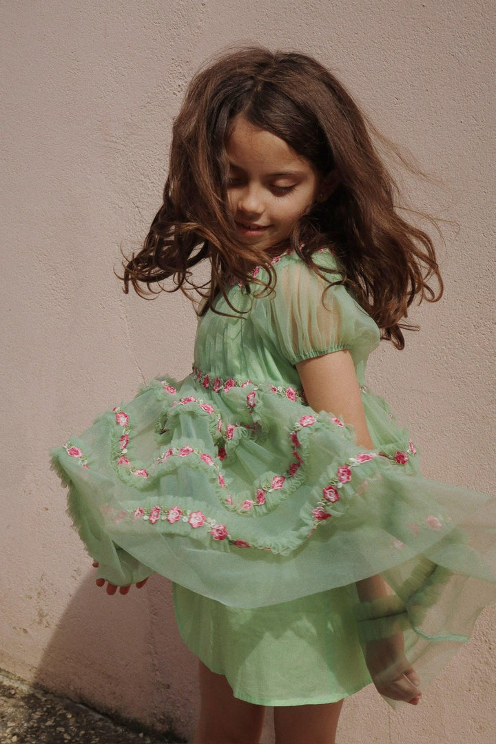 little girl wearing the green tulle dress and twirling so you can see the movement in the dress. 