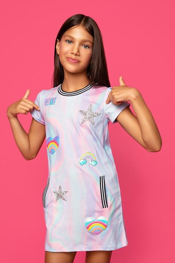 girl modeling the girl's dress with swirls of color and colorful patches on the dress. the dress hits mid thigh