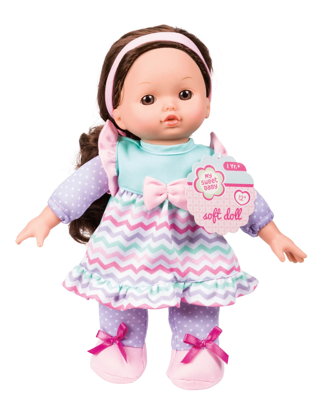 A baby doll with brown hair, wearing a light blue top, a pink and white chevron skirt, and purple polka-dot leggings with pink bows, shown on a white background with its product tag attached.
