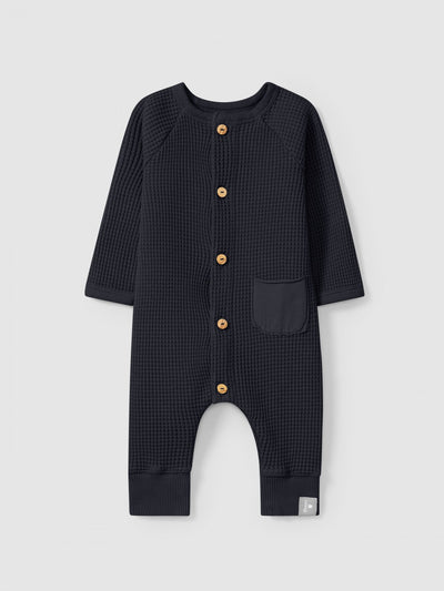 baby romper, waffle cotton in the color navy. wooden buttons going down the center. 