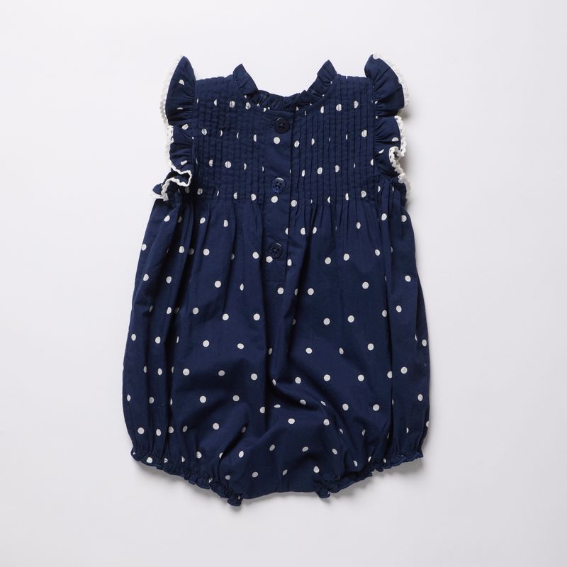 Navy blue romper with white polka dots on a light gray background