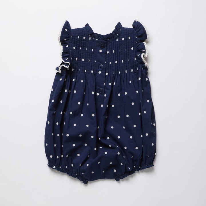 Navy blue romper with white polka dots on a light gray background