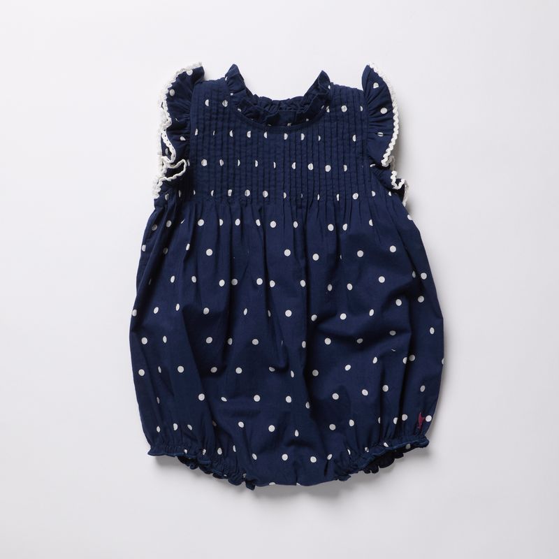 Navy blue romper with white polka dots on a light gray background