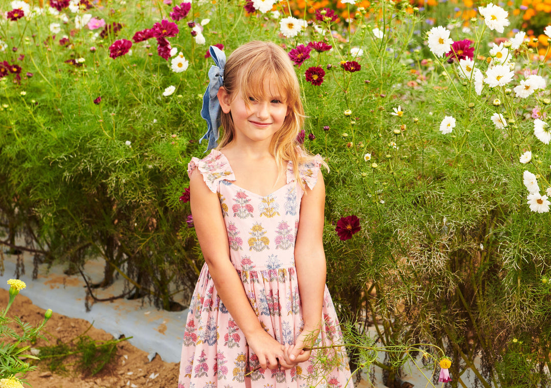 little girl flower wearing the flowerette dress in the garden of flowers. 