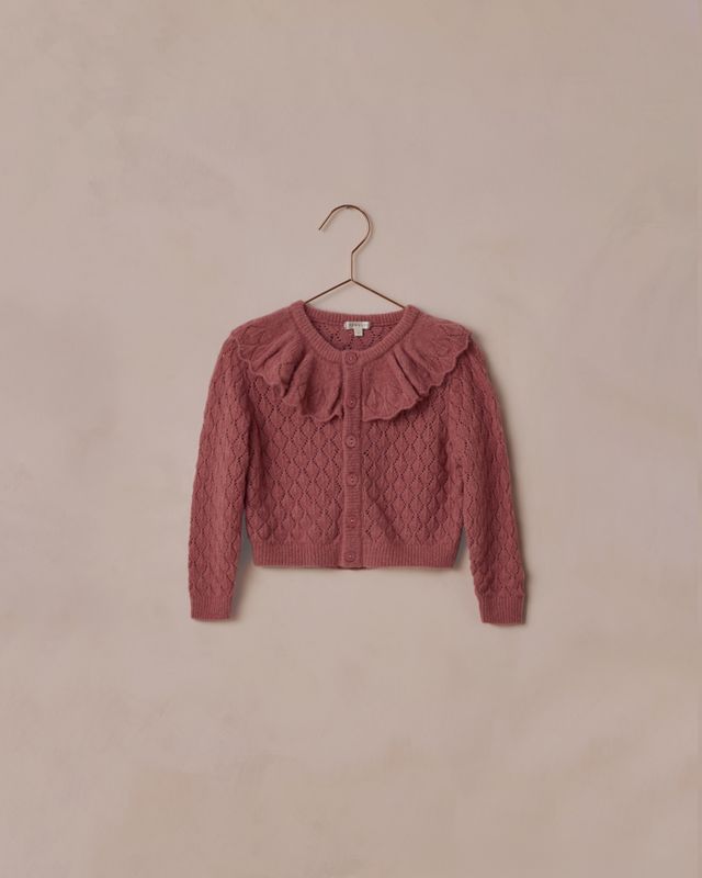 burgundy knitted pointelle sweater with ruffled details on a beige background