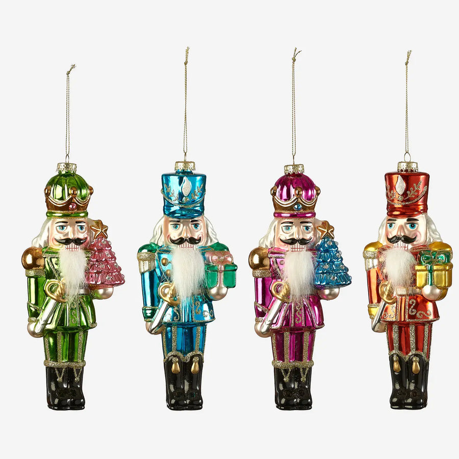 Four colorful nutcracker ornaments in green, blue, pink, and red, each with a white beard and gold hats, shown against a plain light gray background.