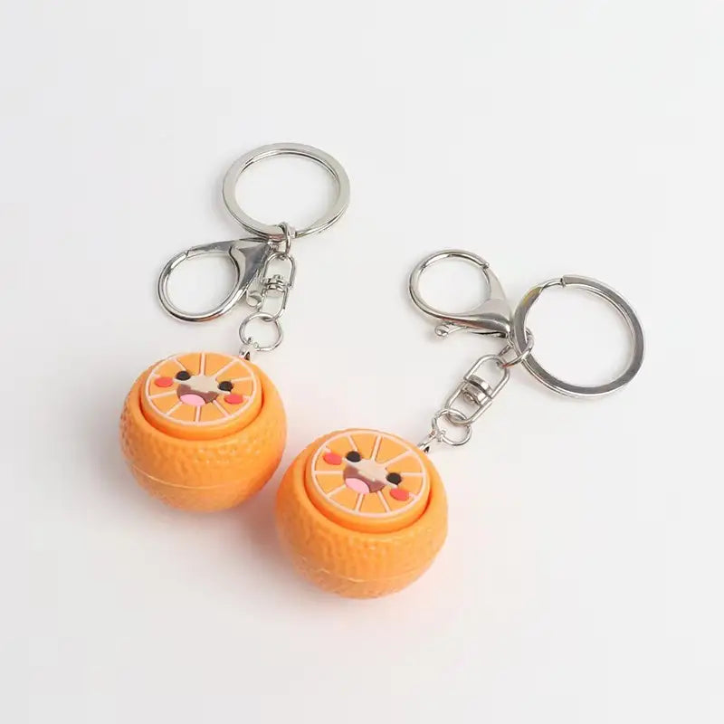Two orange-themed keychains with a cute face design on a light gray background