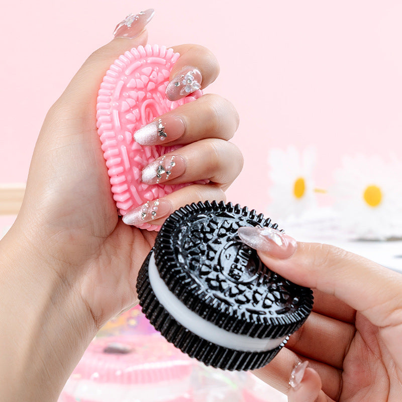 Hand holding two oreos one pink and one black, both squished toys