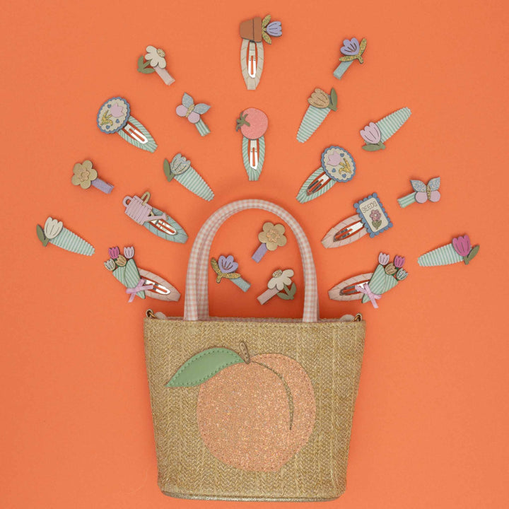 Woven bag with peach design and decorative hair clips on an orange background