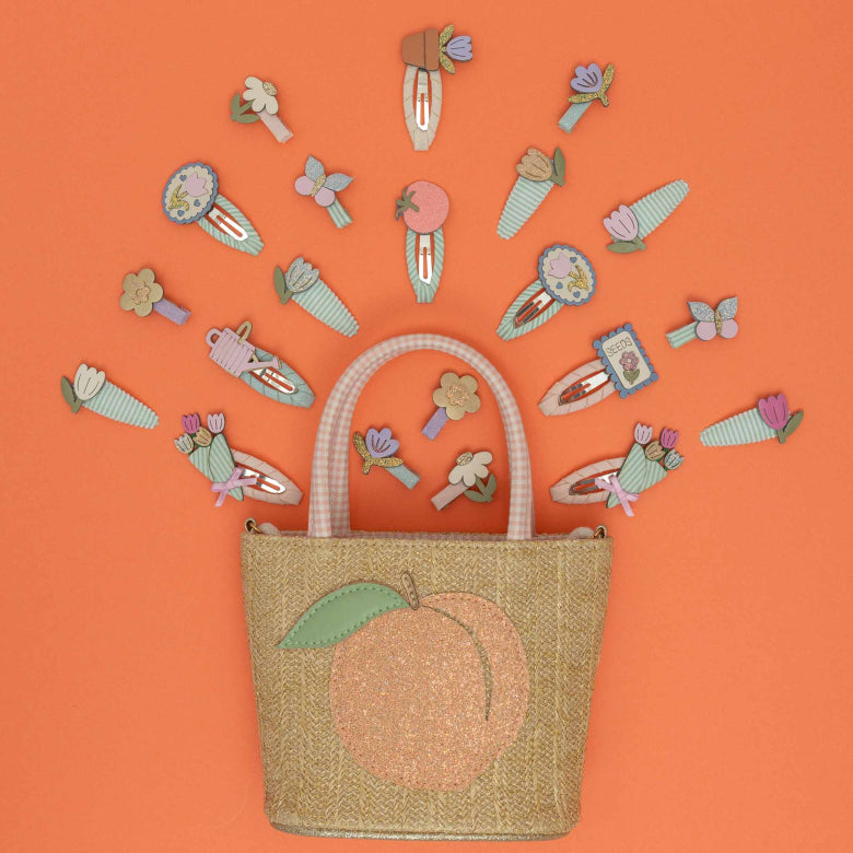 Woven bag with peach design and decorative hair clips on an orange background