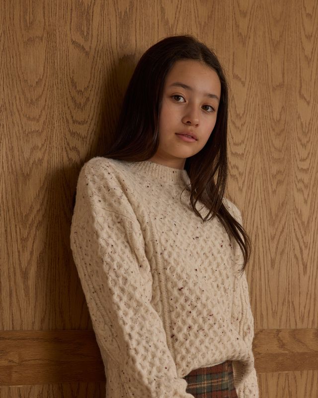 young girl wearing a beige sweater 