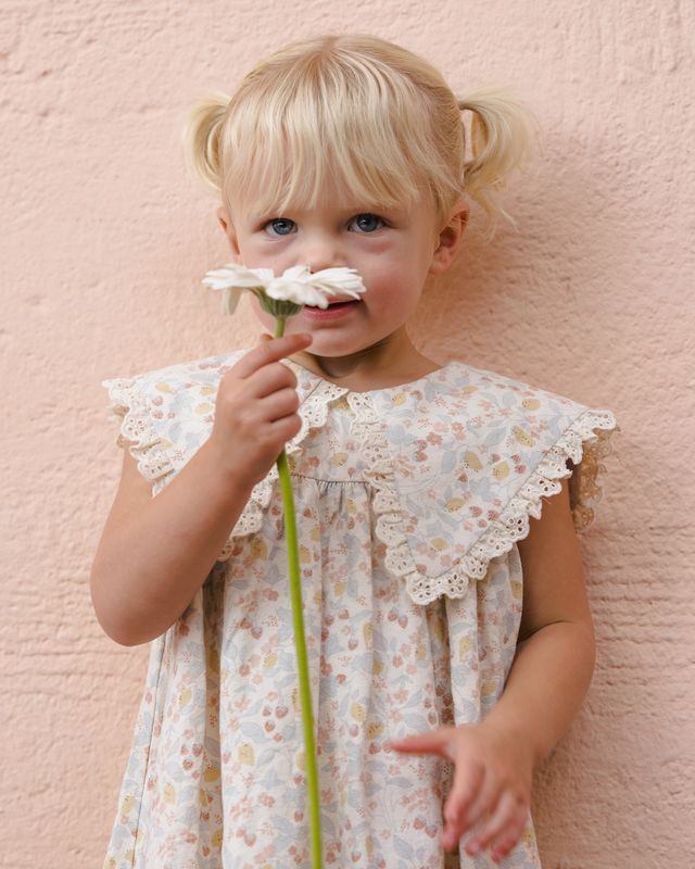 Young girl holding a flower against a pink textured wall