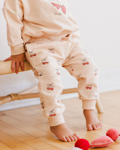 little girl modeling the cherries sweatset. a close up picture of the cherries pattern on the pants. 