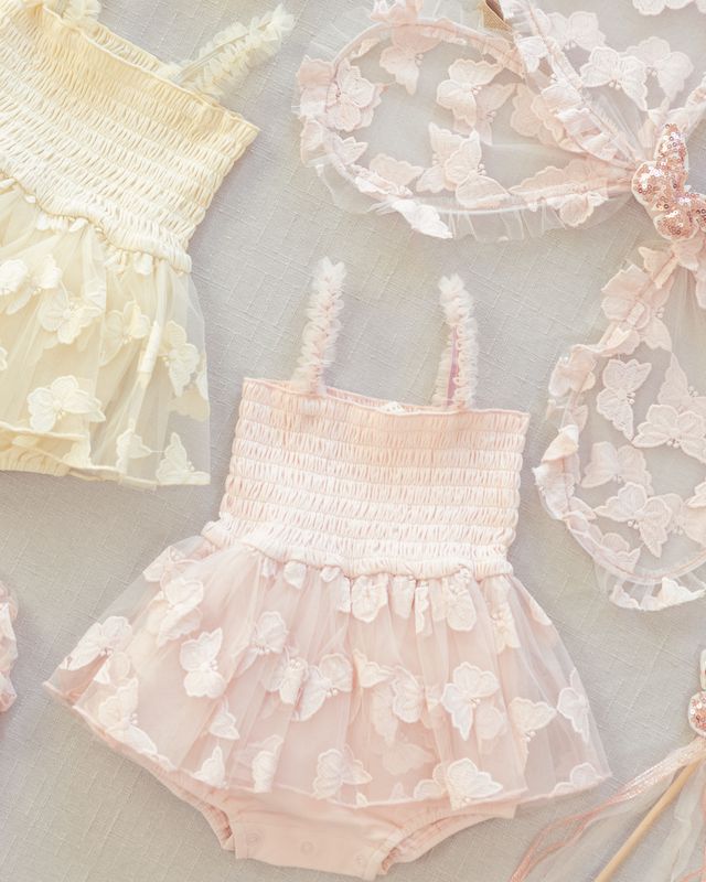 Baby romper with floral details and matching headband on a light background