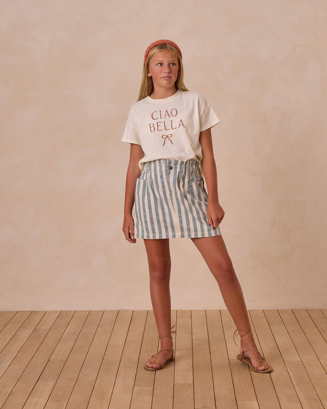 young girl wearing "Ciao Bella" Tee tucked into the ocean stripe skirt. Tee has a nice boxy fit. 