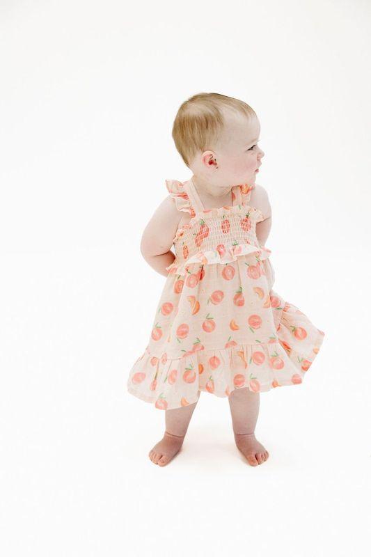 baby modeling the sweet peach dress. this picture shows that there is movement in the dress and hits at the knee