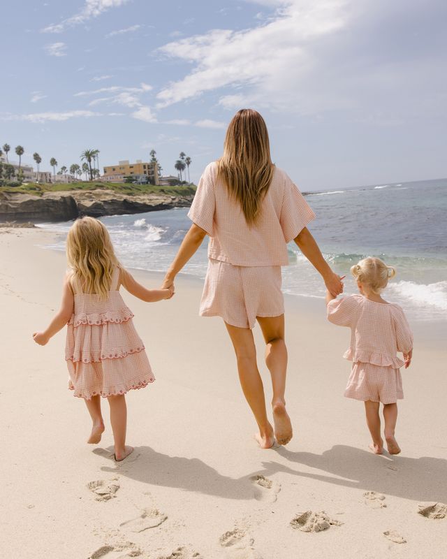 Woman and two children walking on a beach holding hands