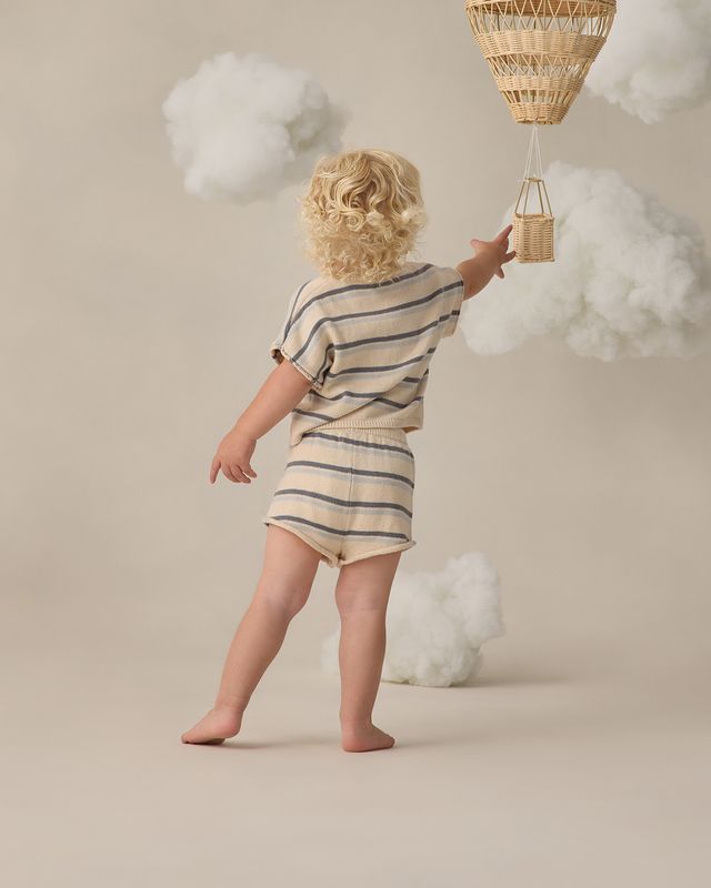 young boy wearing a striped knit outfit from behind