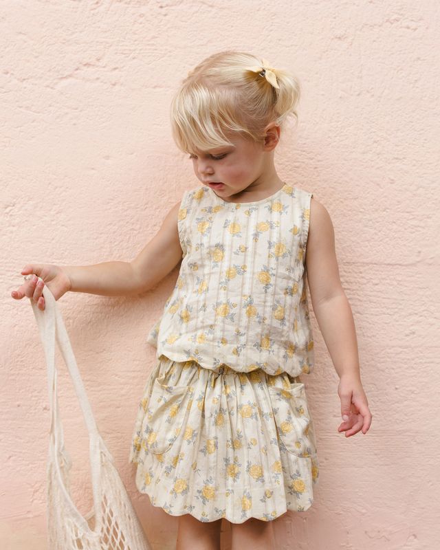 Young girl wearing a floral dress against a pink textured wall