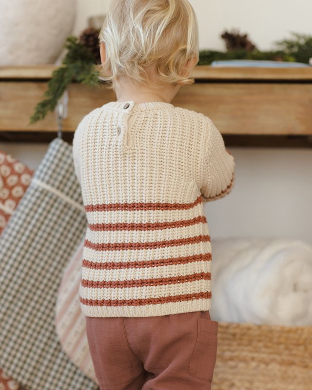 back of Child wearing a striped sweater in a cozy indoor setting