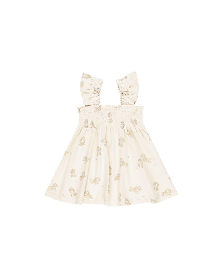 beige dress with smocking on top of the dress and at the sleeves. sleeveless dress with tiny brown puppies all over it. 