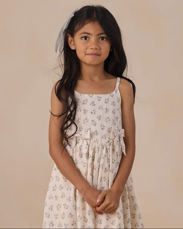 Young girl wearing a floral dress against a plain background