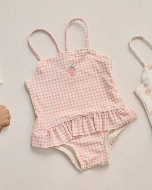 Pink gingham swimsuit with ruffle details on a light background