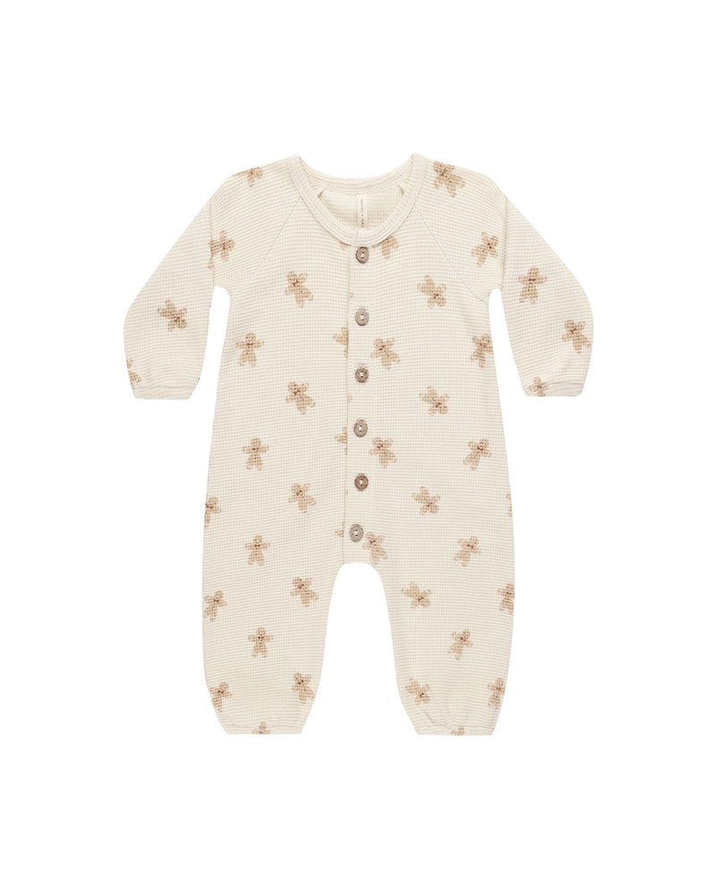 beige organic cotton waffle jumpsuit that buttons down the center with wooden buttons. gingerbread men all over print. 