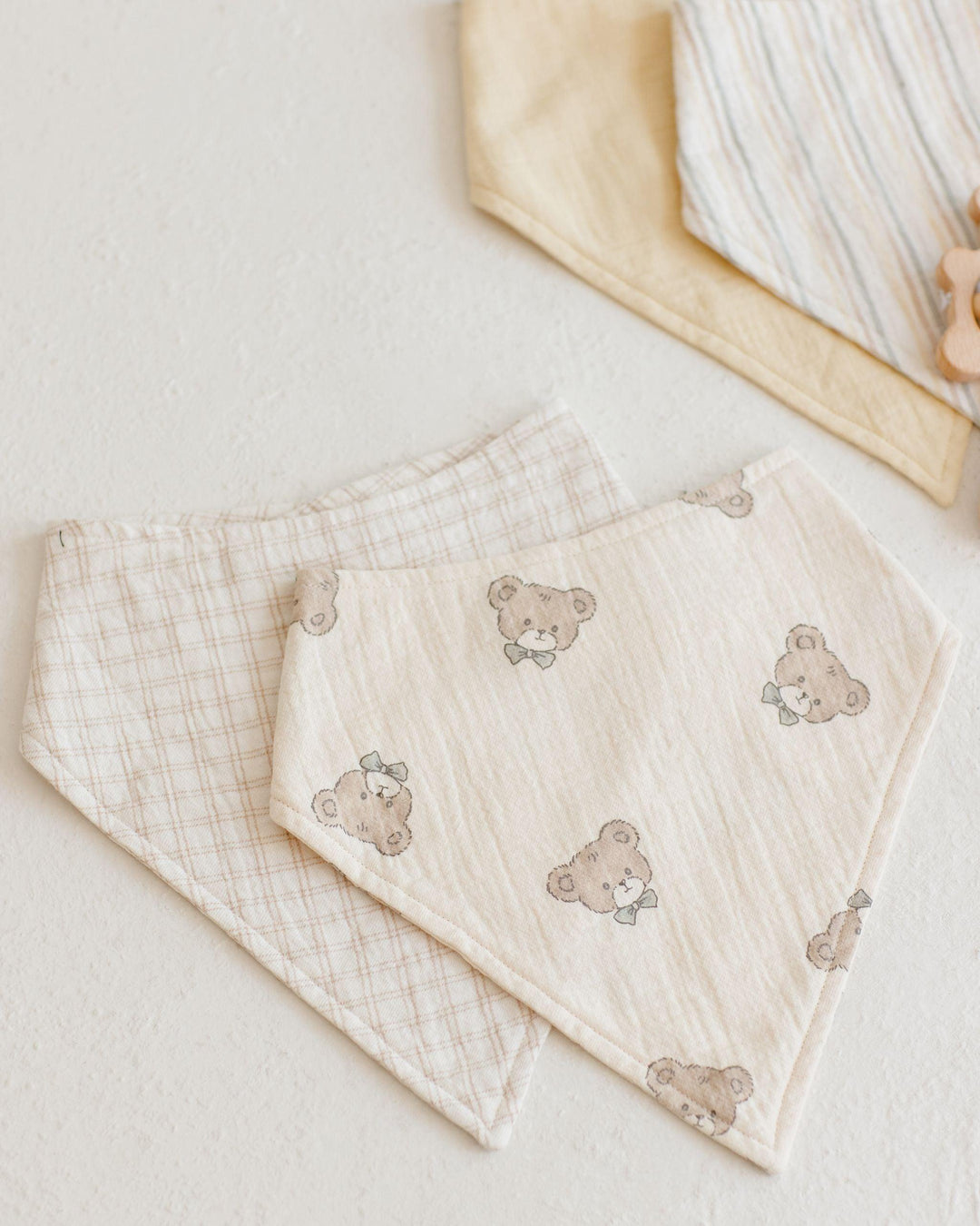 set of two bandana scarf bibs: one bige with teddy bears on it and the other oat check 
