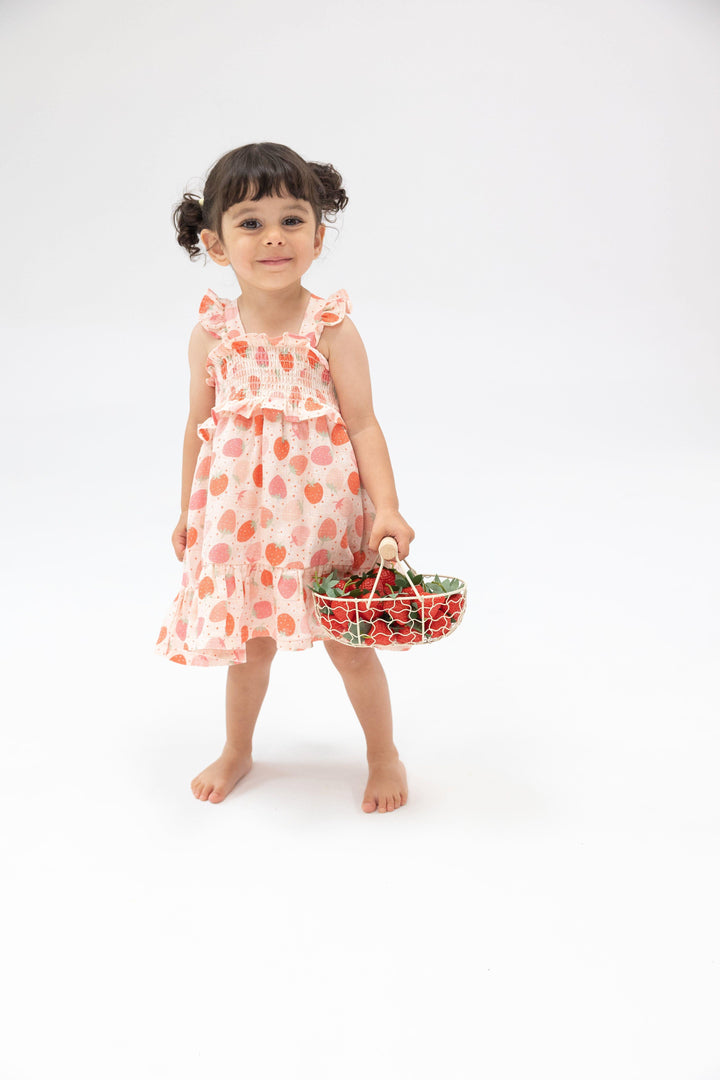 little girl modeling the strawberry smocked sundress, full skirt and smocked top. 