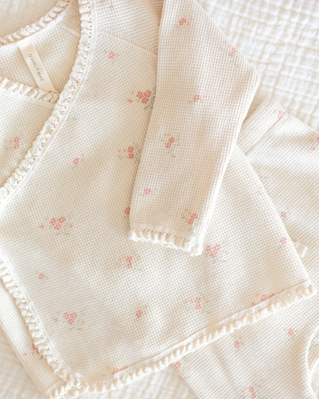 close up of the material and pattern. delicate beige waffle with tiny rosebuds on it. delicate lace trim on the edge