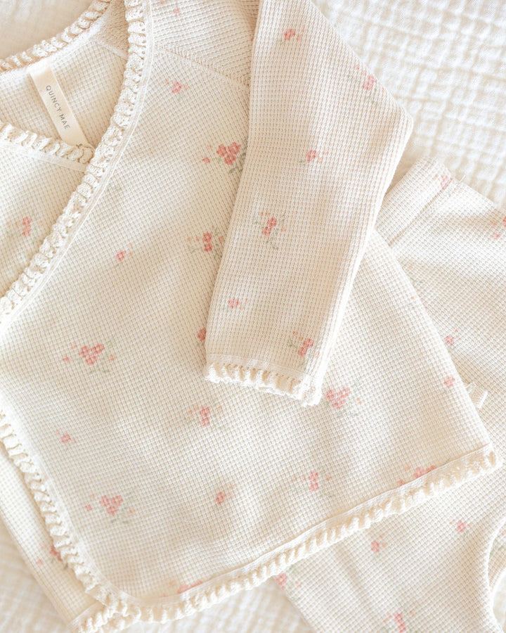 close up of the material and pattern. delicate beige waffle with tiny rosebuds on it. delicate lace trim on the edge