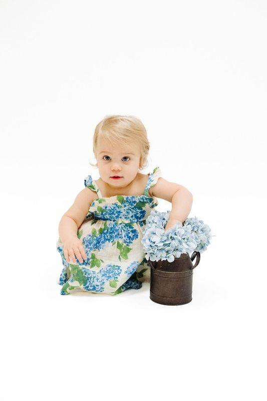 little girl kneeling down in the hydrengea dress showing the vibrant color in the dress.