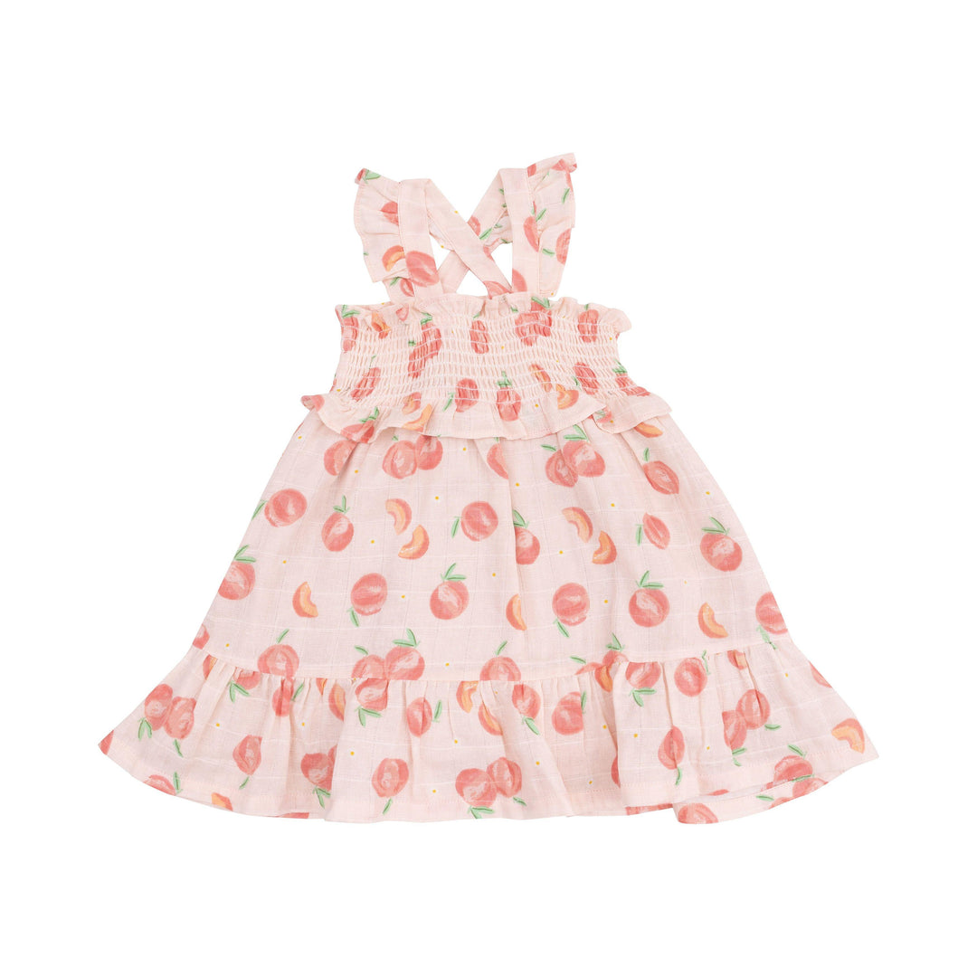 smocked sundress with peach/pink base color and whole/slices of peaches. smocked top with criss cross straps and ruffle at the bottom. 
