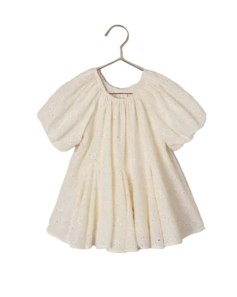 White eyelet dress on a hanger against a beige background