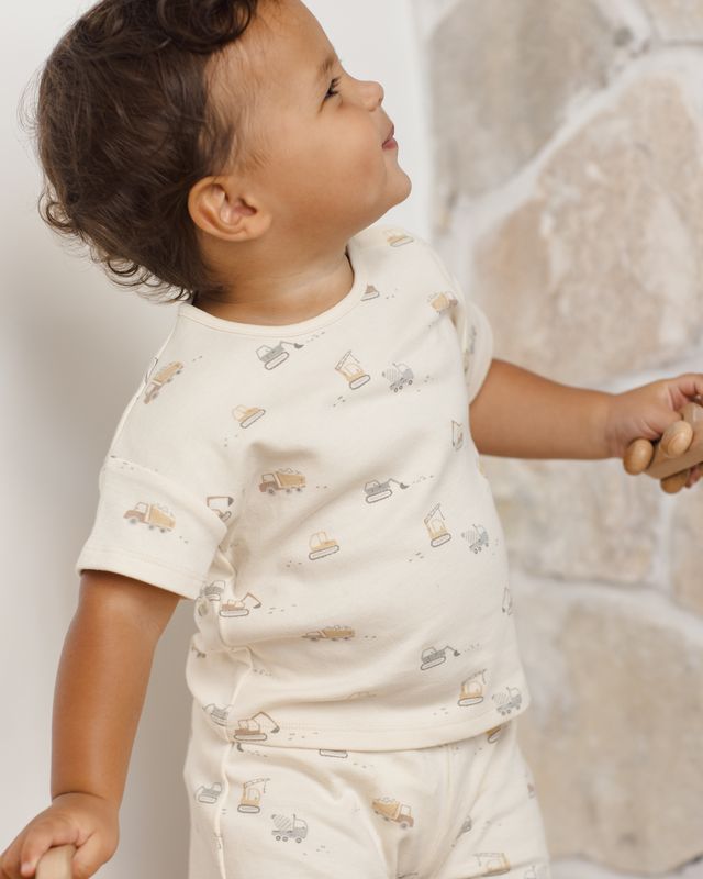 Child wearing a white shirt with small patterns against a neutral background