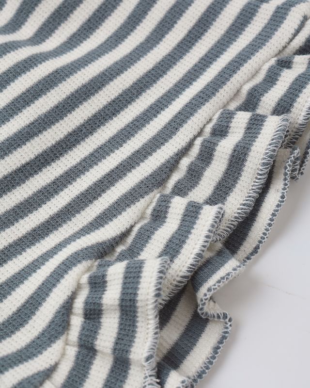 Close-up of a blue and white striped fabric with frayed edges on a white background