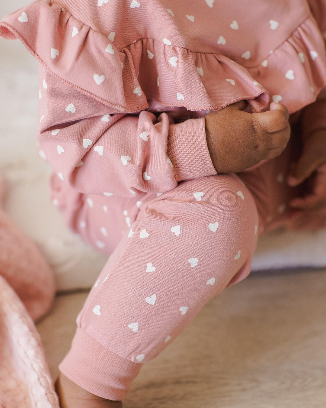 a close up on the color of the sweatsuit which is more of a lipstick pink than true pink . 