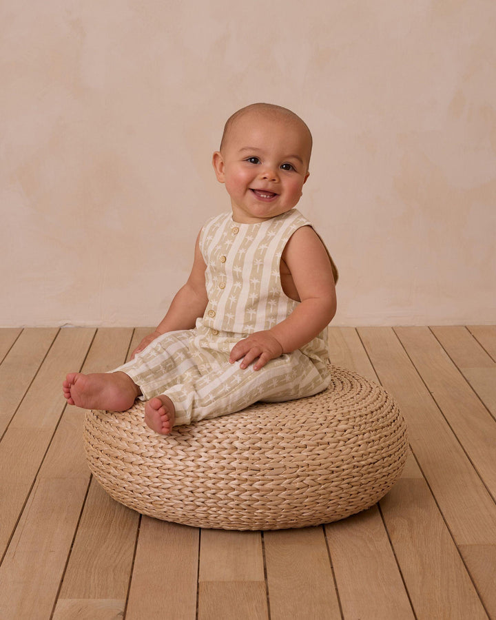 baby sitting in the palm stripe jumpsuit. pants are full length. 