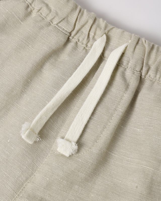 Close-up of beige pants with white drawstrings on a light gray background