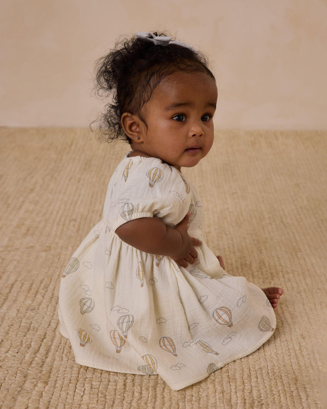 little girl modeling the hot air balloon dress, showing the sleeve is a puff sleeve. 